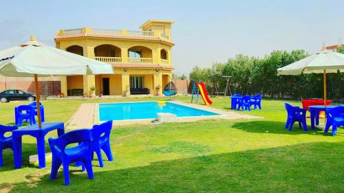 een groep blauwe stoelen en parasols naast een zwembad bij فيلا للايجار في كمبوند سمر قند in El-Qaṭṭa