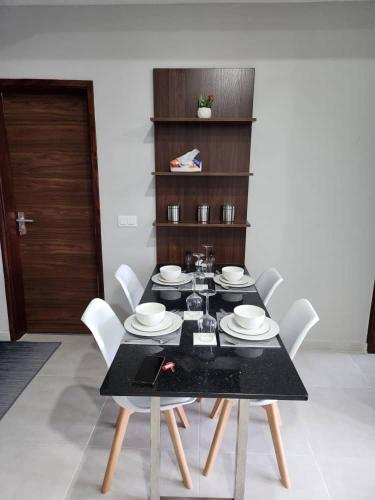 ein Esszimmer mit einem schwarzen Tisch und weißen Stühlen in der Unterkunft Elegant 1 bedroom apartment at Aquaview in Banjul