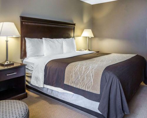 a large bed in a hotel room with two lamps at Comfort Inn & Suites near Tinley Park Amphitheater in Tinley Park