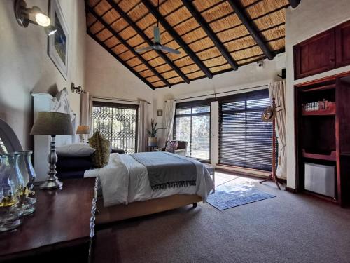 Un dormitorio con una cama y una mesa y ventanas. en The Homestay, en Nelspruit