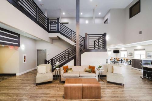 a living room with a staircase and a couch and chairs at Quality Suites Houston Hobby Airport in Houston