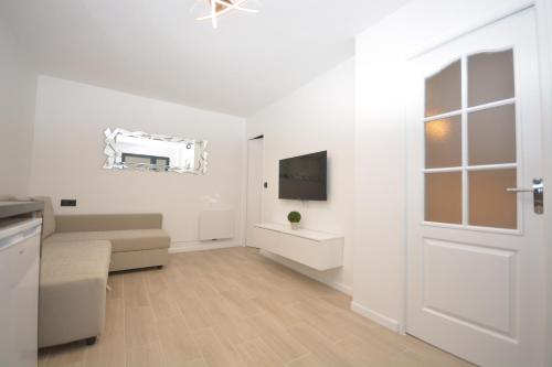 a white living room with a door and a television at 1 Bedroom RDC - Sacre Coeur in Paris
