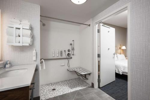 a bathroom with a shower and a sink and a bed at Hampton Inn & Suites - Cape Cod / West Yarmouth in West Yarmouth
