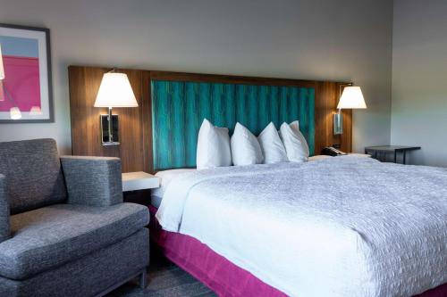 una camera d'albergo con un grande letto e una sedia di Hampton Inn Elkhorn Lake Geneva Area a Elkhorn