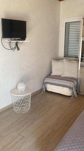 a room with a couch and a tv on a wall at La Caletta di Afrodite in Calabernardo
