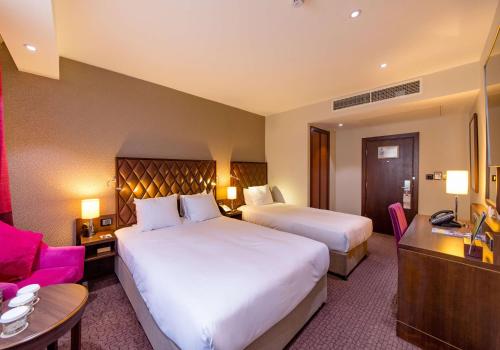 a hotel room with two beds and a desk at DoubleTree by Hilton Hotel London - Marble Arch in London