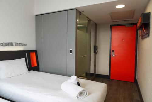 a bedroom with a bed and a red door at easyHotel Ipswich in Ipswich