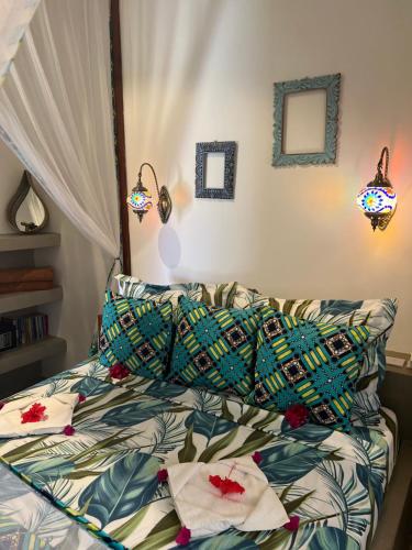 a bed with colorful sheets and pillows in a bedroom at Gadea Boutique Hotel& Gadea Garden Italian Restaurant in Jambiani