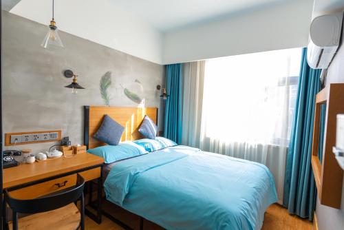 a bedroom with a desk and a bed with blue sheets at Gongxili - Chujian Hotel in Kunming