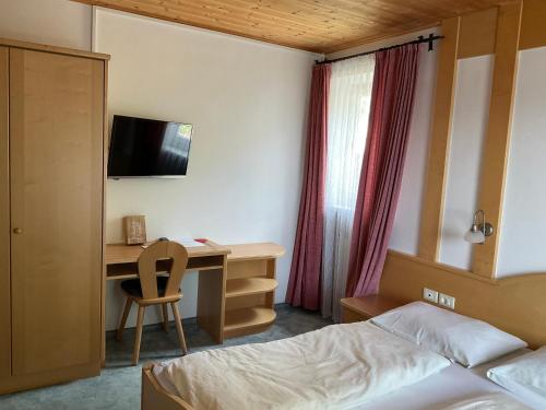 a bedroom with a bed and a desk with a television at Garni Rika in Parcines