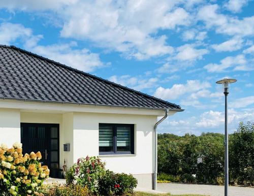une maison blanche avec un toit noir dans l'établissement Ferienwohnung Sea-Bike-Soul, à Neubrandenbourg