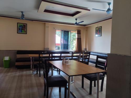 une salle à manger avec des tables et des chaises en bois dans l'établissement Maa River View, à Alīpur Duār