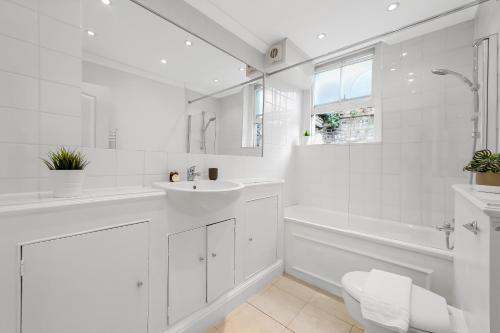 baño blanco con lavabo, bañera y aseo en The Old Street Apartment, en Londres