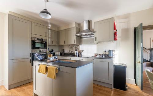 a kitchen with white cabinets and a black counter top at Holmleigh cottage in Tintern