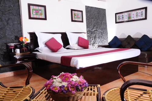 a bedroom with a bed and some chairs and flowers at Punarjani Ayurvedic Resorts in Ramakkalmedu