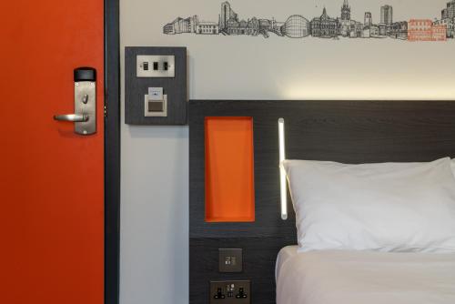 a bedroom with a bed with an orange and black headboard at easyHotel Ipswich in Ipswich