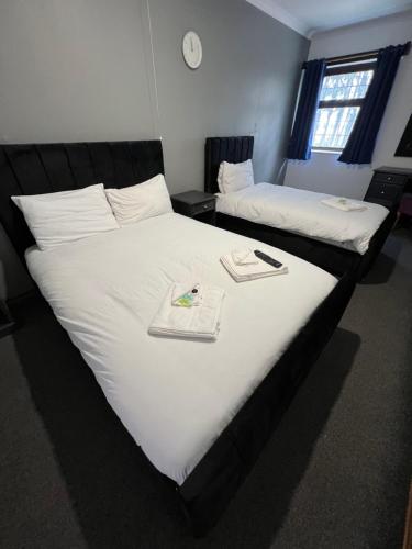 a bedroom with two beds with white sheets and a clock at Stay Inn Express, Cambridge in Cambridge