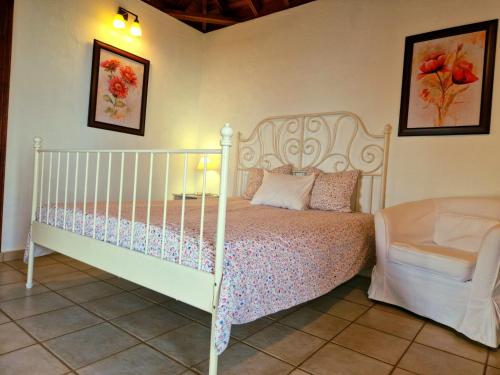 um quarto com uma cama branca e uma cadeira em Casita Canaria con Vista em Breña Baja