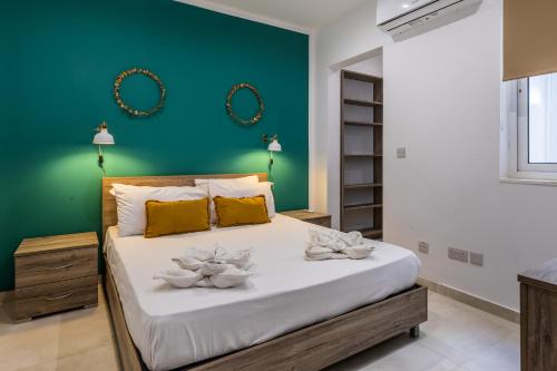 ein Schlafzimmer mit einem großen Bett und einer grünen Wand in der Unterkunft Serafina's Apartment 5 min walk from St Julians in San Ġwann