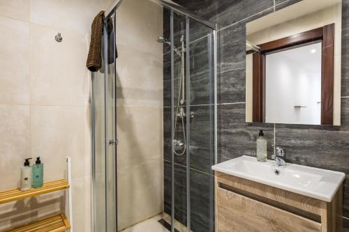 ein Bad mit einer Dusche, einem Waschbecken und einem Spiegel in der Unterkunft Serafina's Apartment 5 min walk from St Julians in San Ġwann