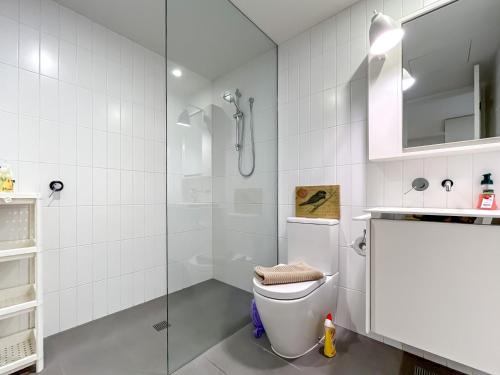 a white bathroom with a shower and a toilet at BPM Brighton APT with Garden LG1 in Melbourne