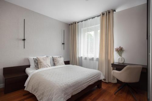 a bedroom with a white bed and a window at Arena Ursynów Luxury Apartment in Warsaw
