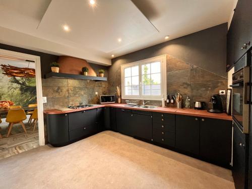 a kitchen with black cabinets and a window at Villa avec pièce Billard style Ranch US in Saint-Fargeau-Ponthierry