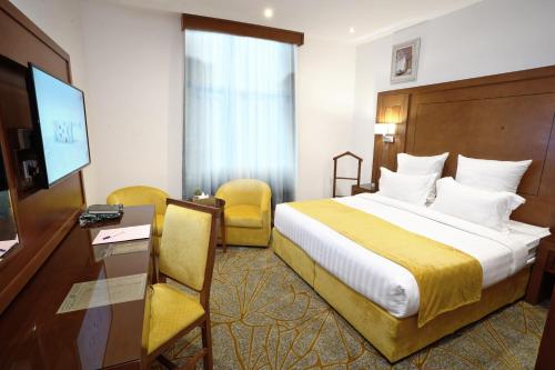 Habitación de hotel con cama, escritorio y TV. en Rose Jeddah Hotel en Yeda