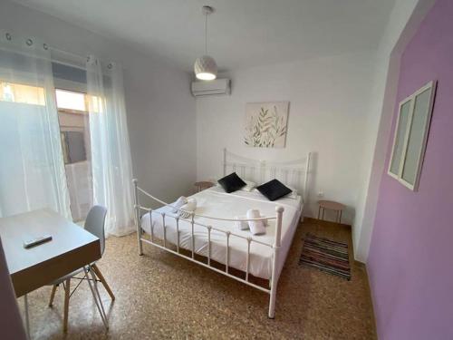 a white bedroom with a white bed and a desk at NEW! Flower Patio House 2 BDR - BBQ - Wash machine in Lavrio