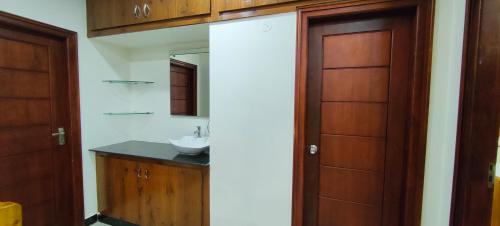 a bathroom with a sink and a wooden door at Magnolia Villa Luxury 3 Bedroom Apartments in Visakhapatnam