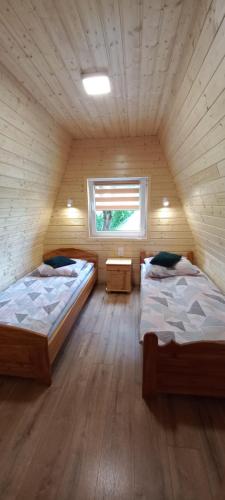 ブコビエツにあるBieszczadzkie domkiの木造キャビン内のベッドルーム1室(ベッド2台付)