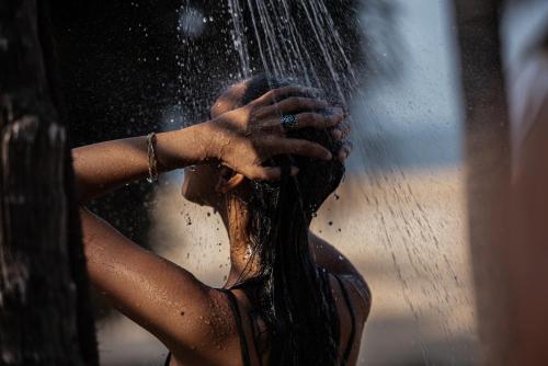 a woman is standing under a water shower at Neeleshwar Hermitage in Nīleshwar