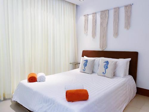 a bedroom with a large white bed with orange accents at Beachfront 2br 2bath apartment private plunge pool 50 meter to Naithon beach in Nai Thon Beach
