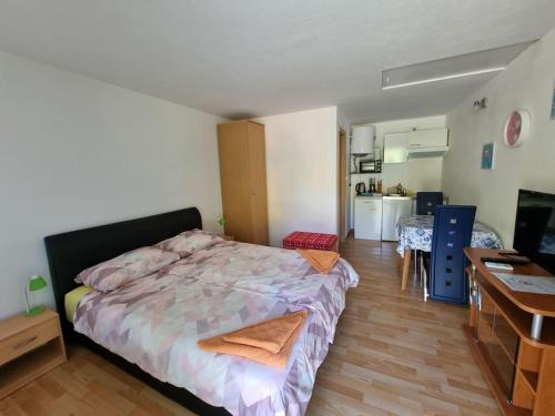a bedroom with a bed and a desk and a kitchen at Apartma Patricija for 2 in Tolmin