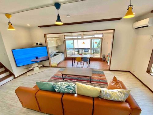 a living room with a couch and a large screen tv at 露天風呂オーシャンビューBlue Ocean IZU in Ajiro