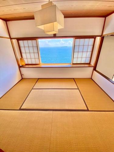 an empty room with a window and the ocean at 露天風呂オーシャンビューBlue Ocean IZU in Ajiro