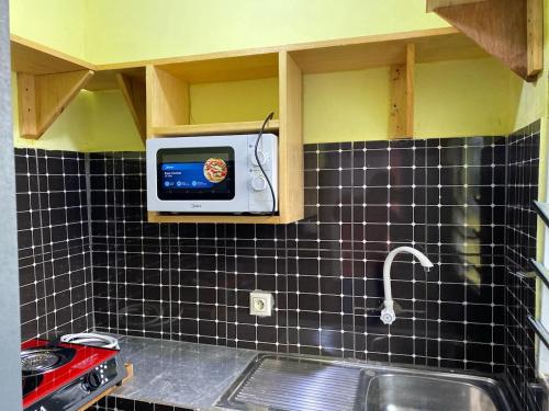 een keuken met een wastafel en een tv aan de muur bij Studio meublé in Douala