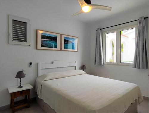 a white bedroom with a bed and two windows at Apartamento en el campo de golf Son Parc, Menorca in Son Parc