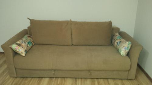 um sofá castanho num quarto com duas almofadas em Kuca radovanovic em Tekija