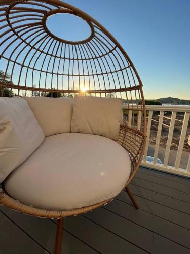 a rattan chair sitting on a balcony with the sun setting at Hot Tub - Saugatuck - Douglas - Luxury Home Sleeps 8 in Douglas