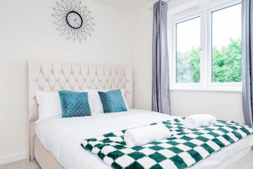 a white bedroom with a checkered blanket on a bed at Modern, Spacious House with Free Parking & Garden in Swindon