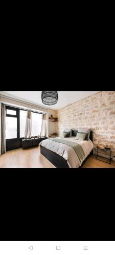 a bedroom with a large bed and a stone wall at IMHOST - Amazing architect studio Père Lachaise in Paris