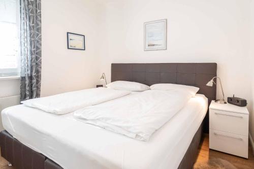uma grande cama branca com lençóis e almofadas brancos em Haus am Kirchenweg em Wenningstedt