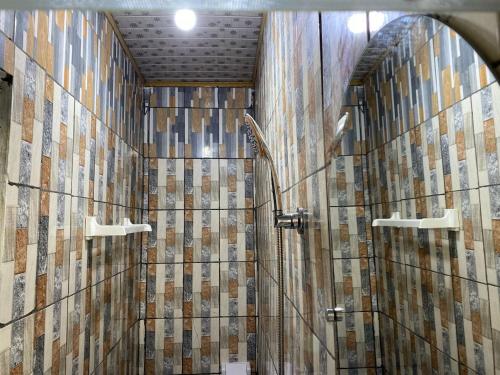 een badkamer met een douche en betegelde muren bij Studio meublé in Douala