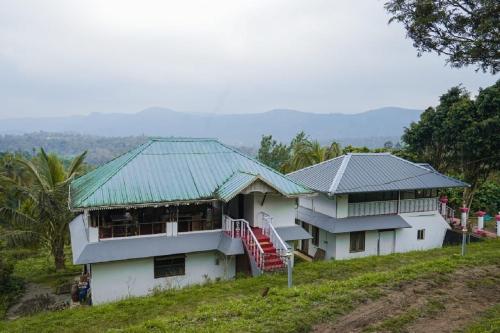 two white houses with green roofs on a hill at Punarjani Ayurvedic Resorts in Ramakkalmedu
