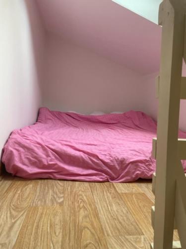 um quarto com uma cama rosa e piso em madeira em Appartements sympas et confortables em Nanterre