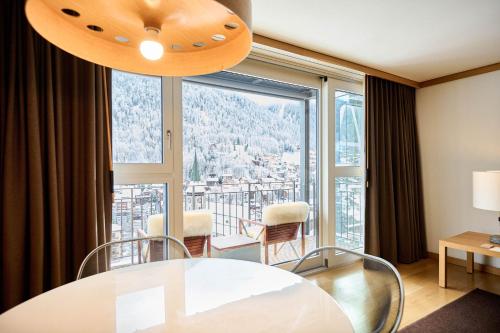 a dining room with a table and a large window at The Omnia in Zermatt