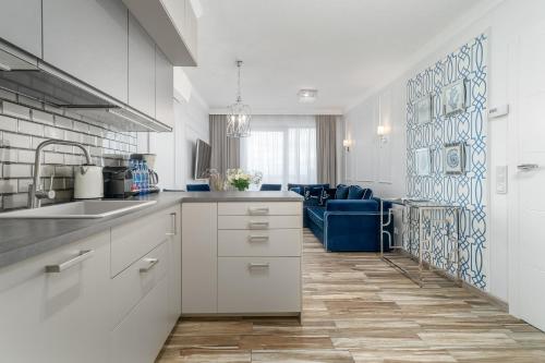 een keuken met witte kasten en een blauwe bank bij Your Holidays Promenada Gwiazd 14 in Międzyzdroje