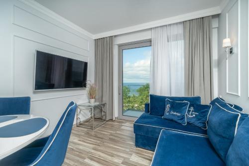 a living room with blue furniture and a large window at Your Holidays Promenada Gwiazd 14 in Międzyzdroje