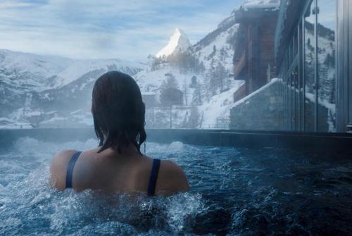 una mujer en una piscina con vistas a una montaña en The Omnia, en Zermatt